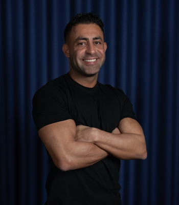 Ismail, centerleder hos Black Swan Lifestyle. Ismail står og smiler med armene over kors iført en sort t-shirt